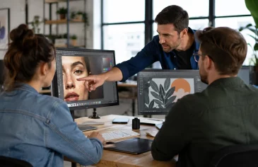 Formation design graphique : un formateur et deux participants devant des logiciels de création graphique